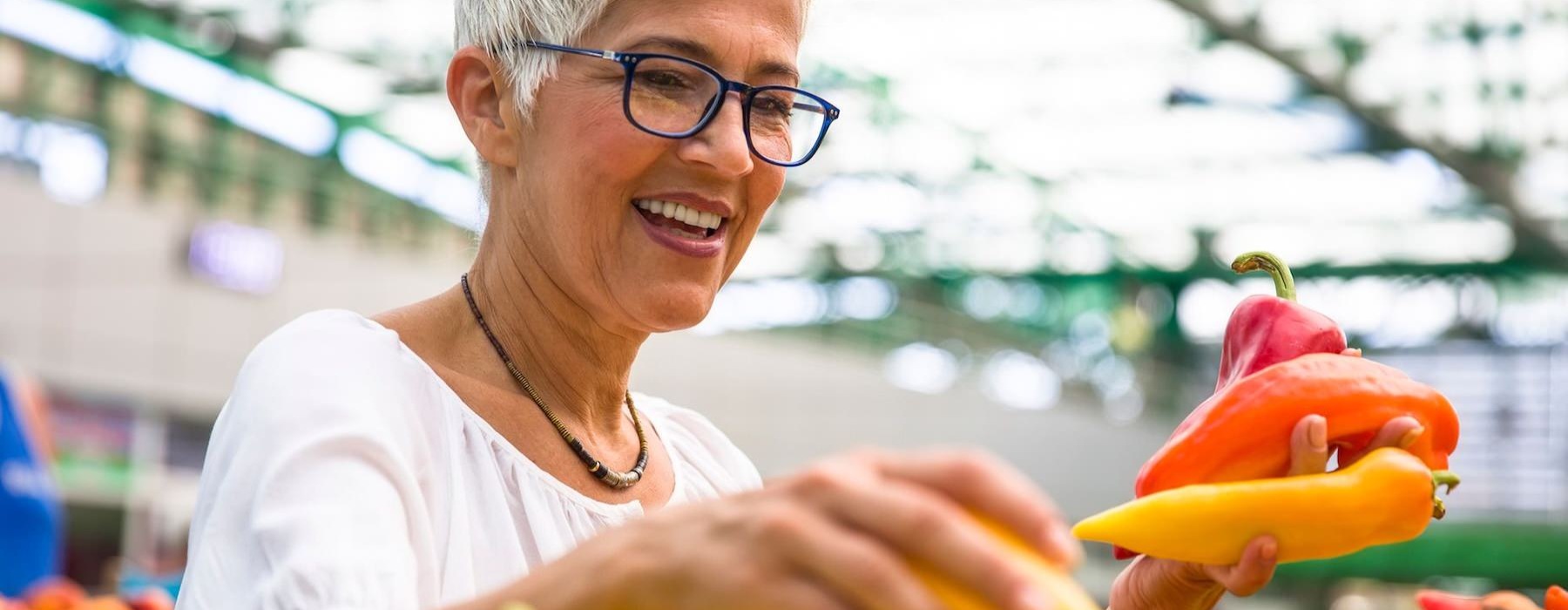a woman smiling and holding a bunch of vegetables